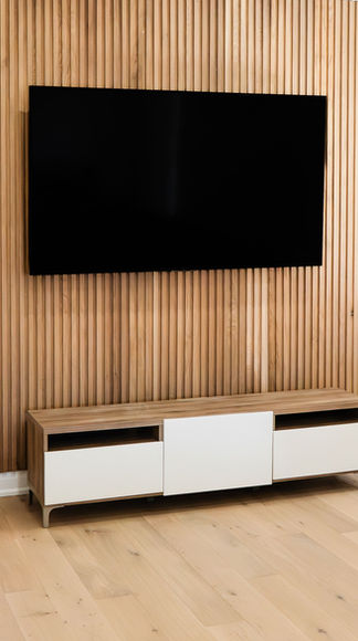 White oak wood slat wall and custom credenza with matching engineered white oak flooring in a living room renovation.