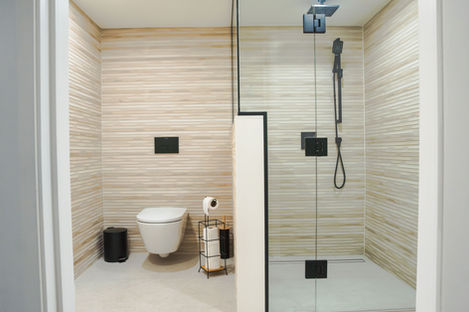 Complete Vaughan bathroom renovation featuring a floating toilet, walk-in glass shower, and wood-look textured tile.