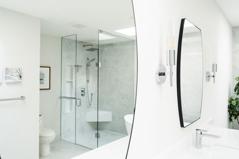 Artistic reflection in a custom bathroom mirror showing a high-end glass shower enclosure and luxury tile work.
