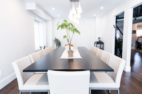 Close-up of a black oak dining table with a money tree centerpiece and white upholstered chairs in Thornhill.