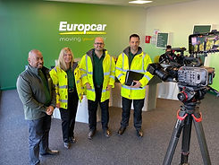 a group of people stood infront of a Europcar logo being filmed 