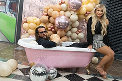a man sat in a bath full of balloons