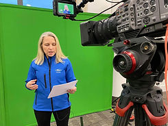 a woman wearing a blue jacket stood in front of a green screen