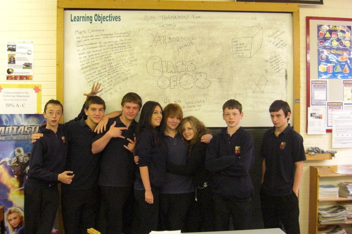 5 boys and three girls stood in front of a whiteboard in a school classroom. Class of 08 written on the board.