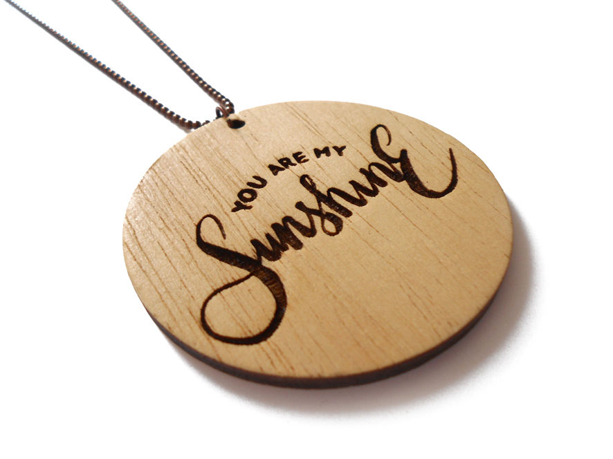 Κολιέ "You are my Sunshine" από ξύλο σε φυσικό χρώμα, με χάραξη & επιμεταλλωμένα ορειχάλκινα στοιχεία. Διάμετρος: 5 cm, μακρύ