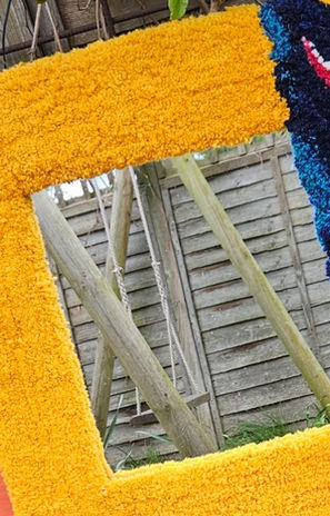 Seasons of Summer Tufted Mirror by Ryka Design close-up detail showing bold golden yellow hand-tufted Axminster wool frame photographed outdoors in garden setting