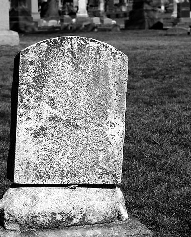 Worn and weathered, simple and plain, natural stone tombstone with a blank epitaph and roo