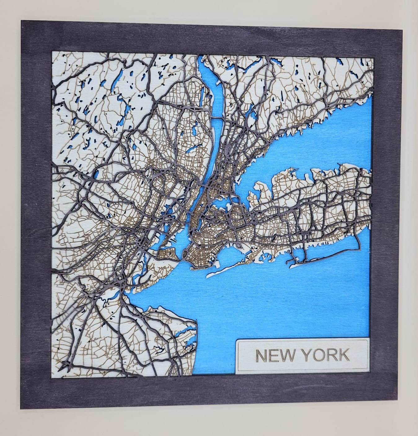 3D laser-cut NY map, plywood wall art with blue water base and dark oak frame.