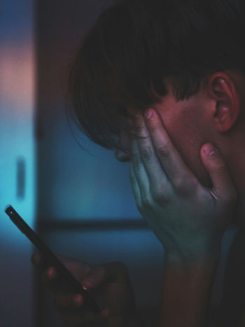 a teenage boy looking in distress at his phone