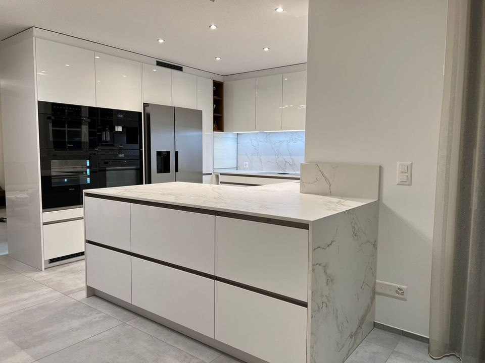Weisse Küche von PBK DESIGN, 5610 Wohlen AG, mit weiss marmorierter Arbeitsplatte, Edelstahlgriffen, Food Center und Einbaugeräten, funktional und elegant.