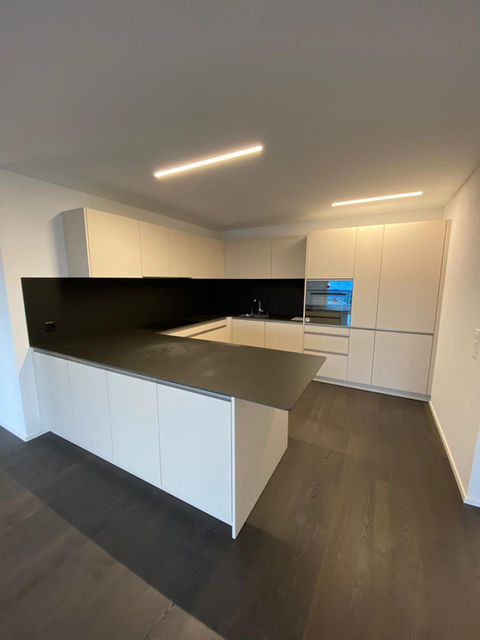 Weisse Küche von PBK DESIGN, 5610 Wohlen AG, mit dunkler Arbeitsplatte, modernes Design, klare Linien und funktionale Gestaltung.