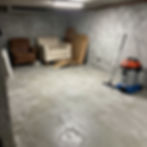 Clean concrete basement floor with armchairs and vacuum.