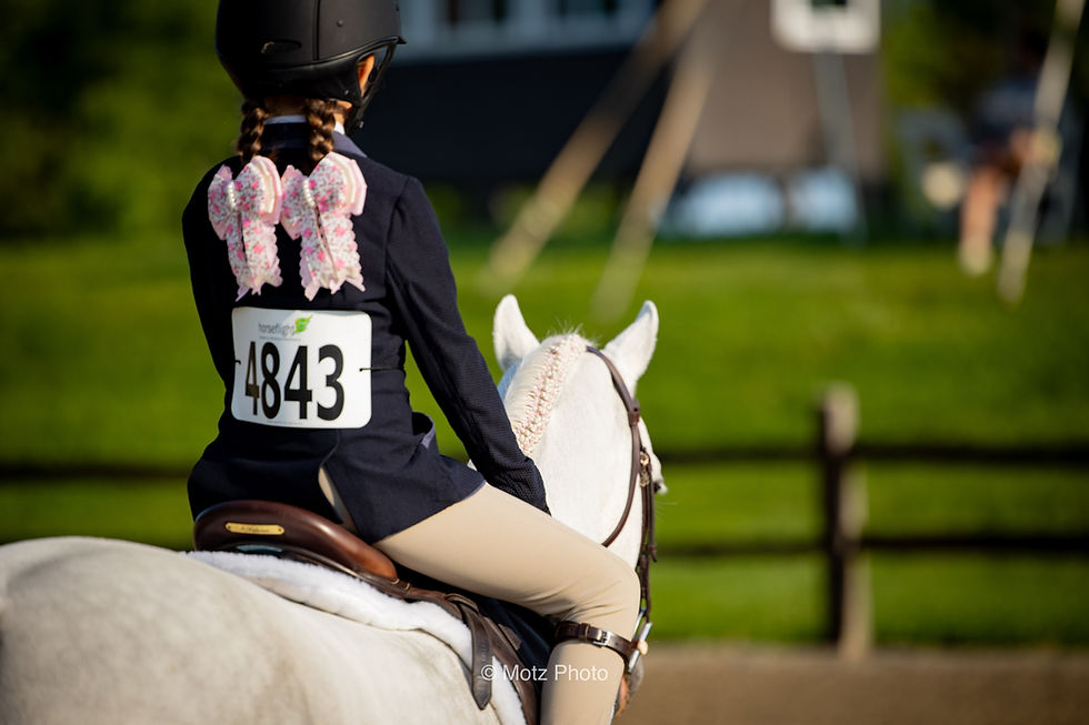 Young rider wearing number 4843 on a white horse