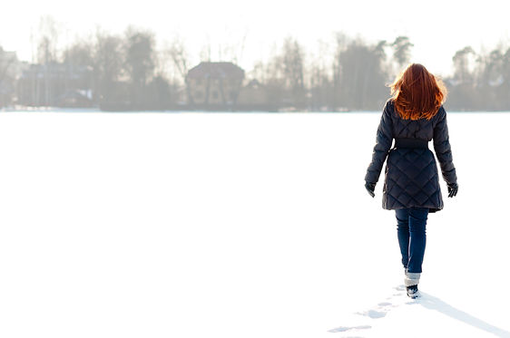 Pretty red haired girl walking on frozen lake and making footpath (1).jpg