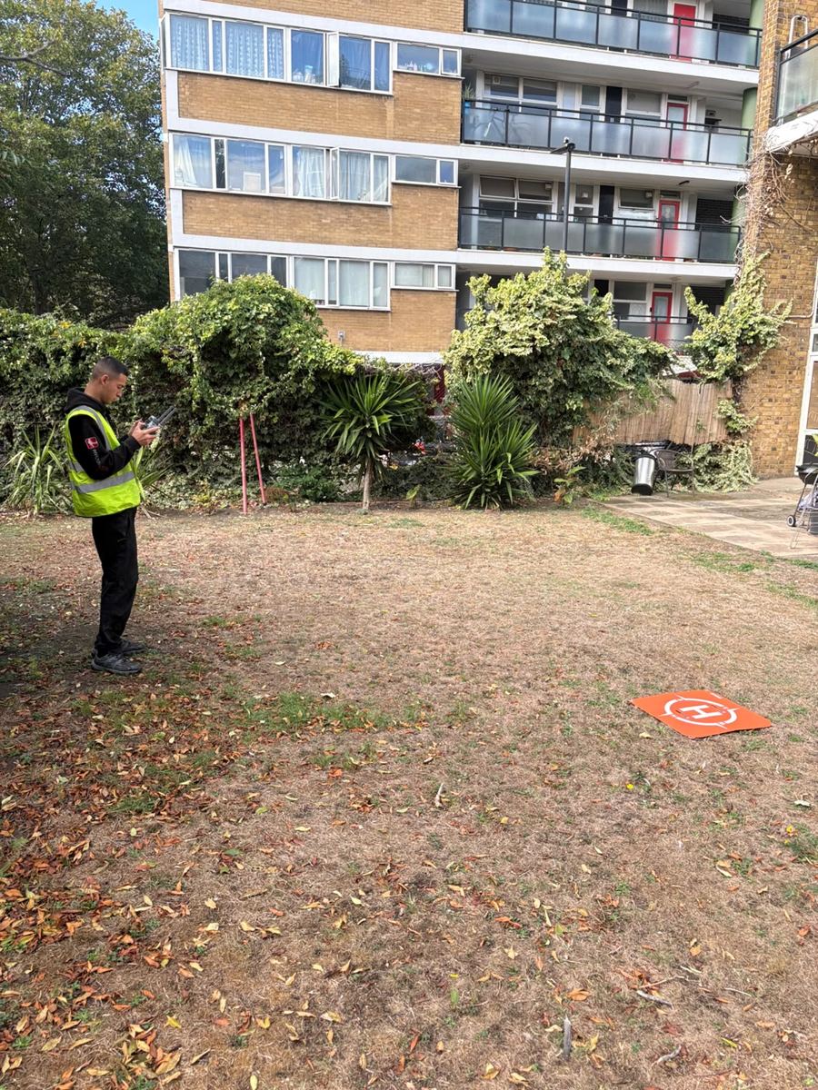 Drone pilot in hi-vis at a controller beside an orange landing pad