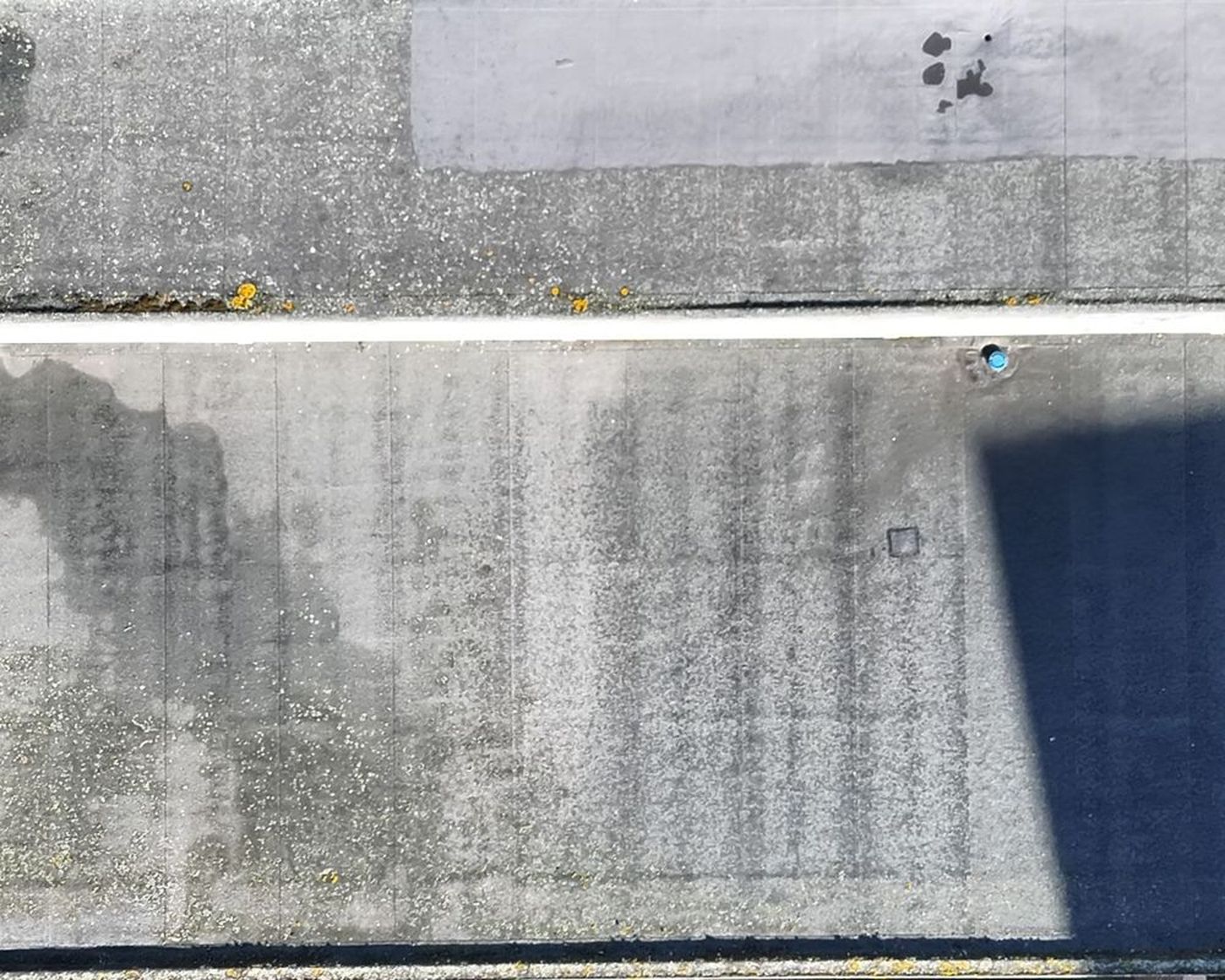 Visual drone image of a flat felt roof with an arch-shaped tide mark from an outlet
