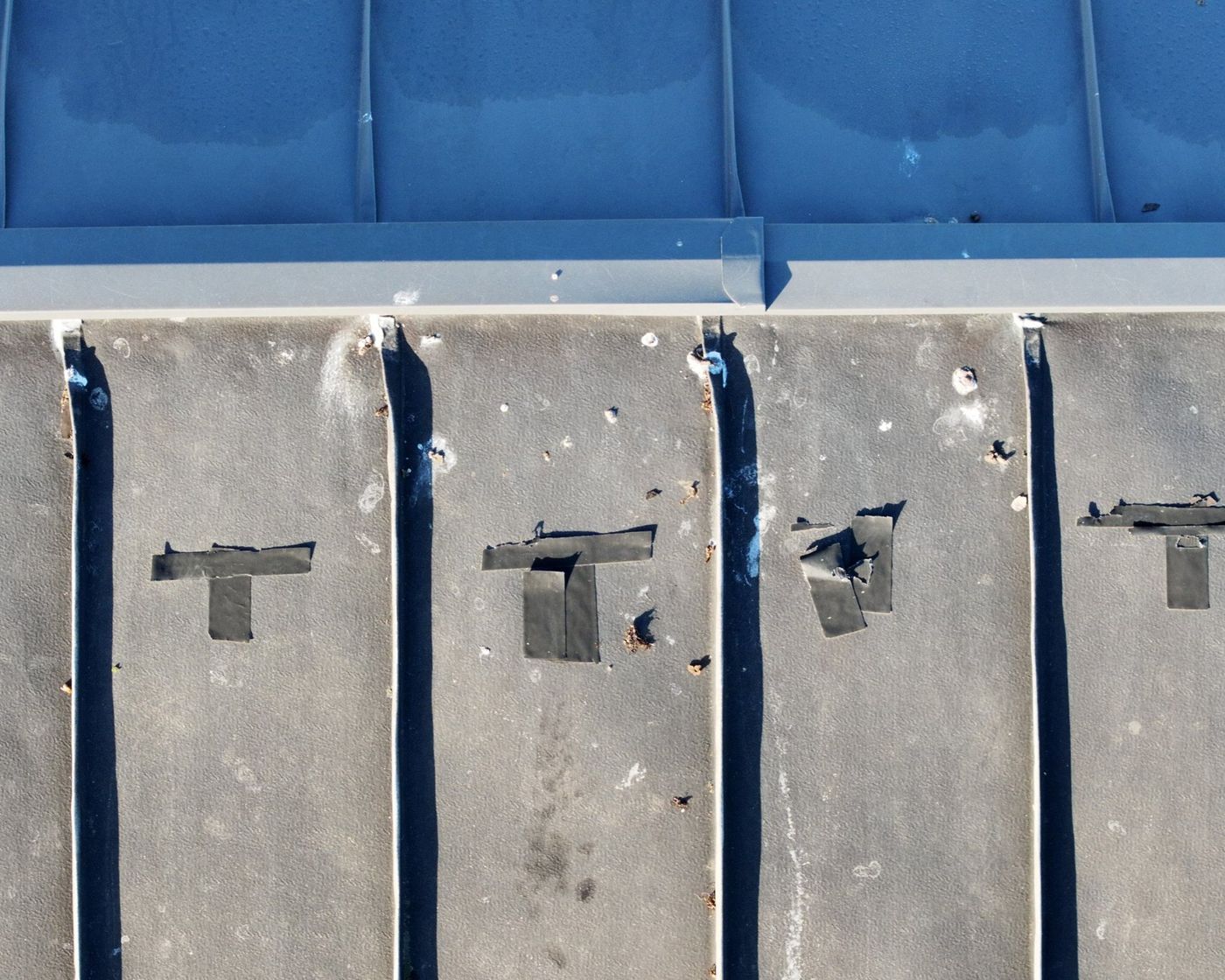 Drone photo of membrane roof seams with black tape patches below the ridge