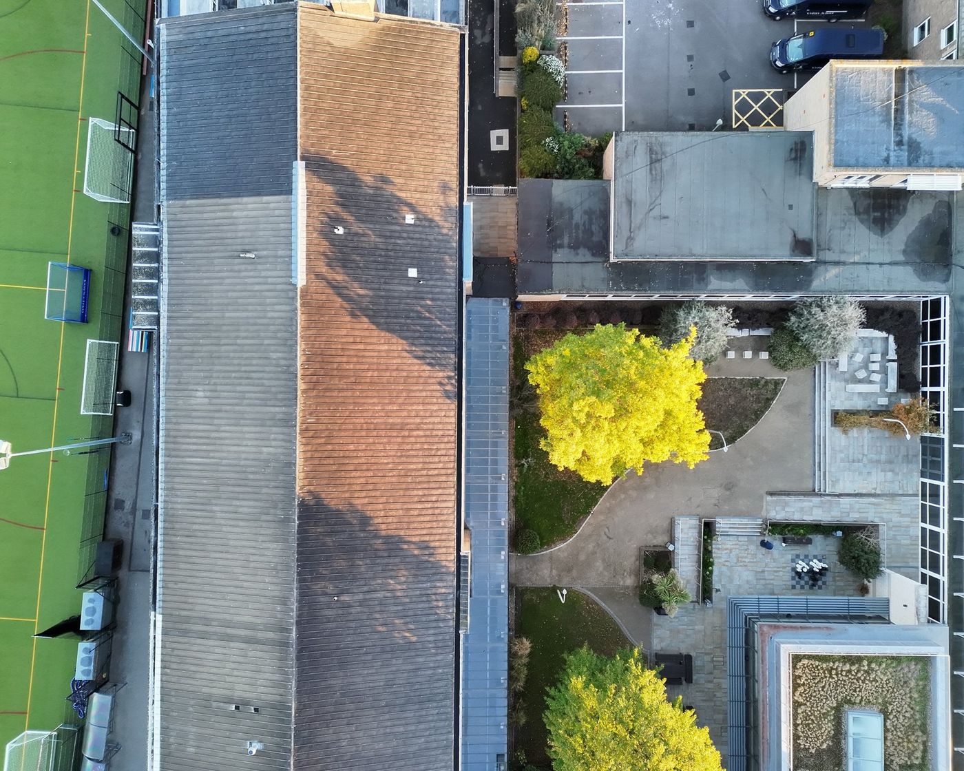 Drone overview of a long pitched school roof beside a sports pitch