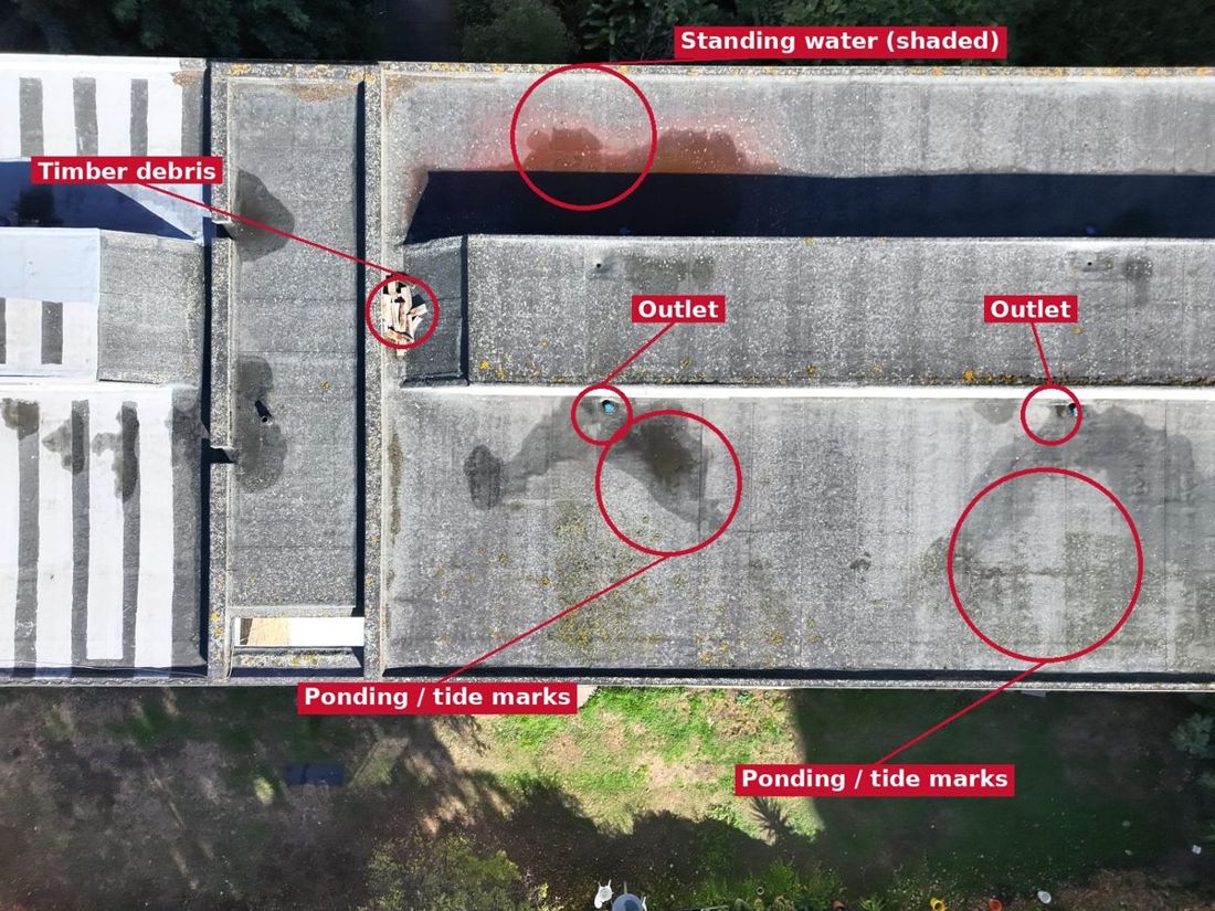 Annotated drone photo of a flat roof marking tide marks, standing water and debris