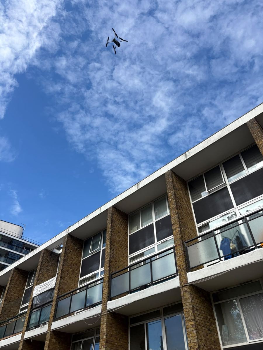 Survey drone flying above the parapet of a brick building