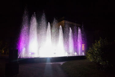 Fontaine illuminée en violet et blanc la nuit