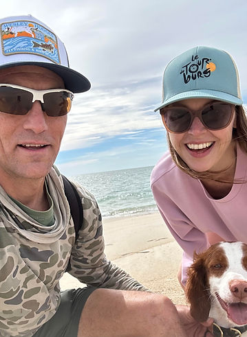 Kari and Mike Carpenter, owners of yoga sol with their brown and white dog on a beach