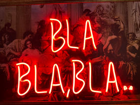 Red neon sign reading “BLA BLA BLA..” placed over a classical-style painting of reclining figures and Roman architecture.