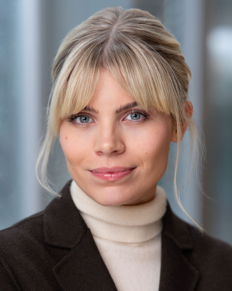 A portrait of a businesswoman in front of an office environment backdrop