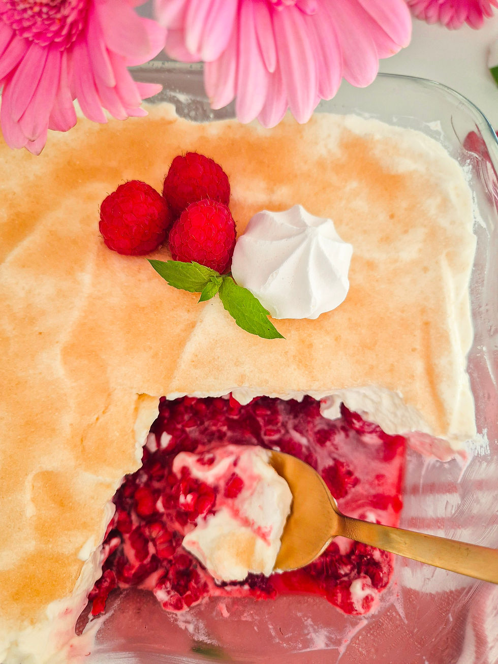 Cremiges Himbeerdessert in Glasform mit Löffel, frischen Himbeeren, Sahne und pinken Blüten, fröhlich und appetitlich.