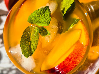 Pfirsich Eistee mit Pfirsichspalten und Minze in einem Glas, warmes goldenes Licht, frische Sommerstimmung