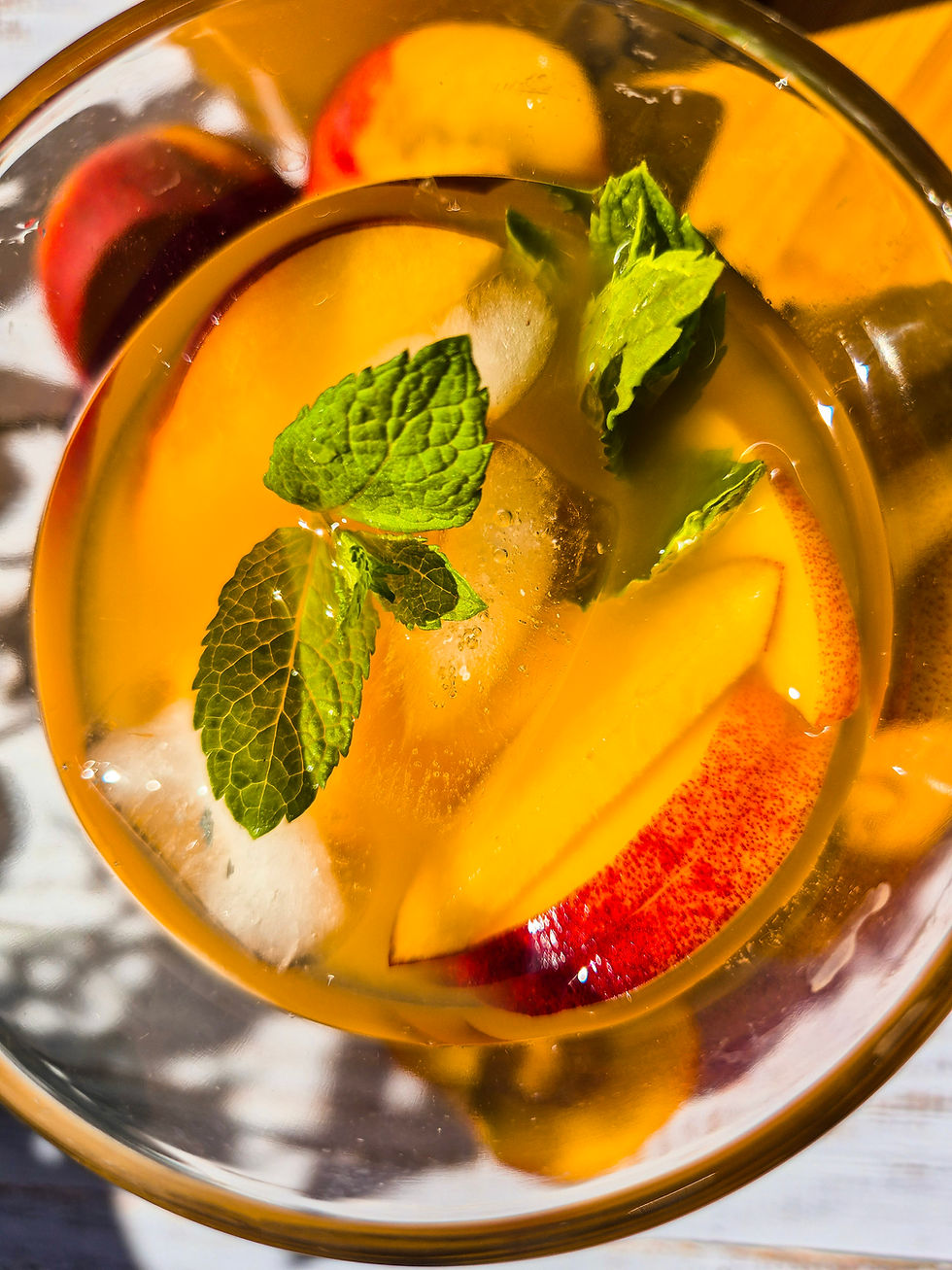 Pfirsich Eistee mit Pfirsichspalten und Minze in einem Glas, warmes goldenes Licht, frische Sommerstimmung