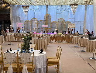 Banquet hall with chandeliers and white chairs by Kauvery Events
