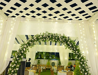 Green floral arch and venue decoration for a wedding by Kauvery Events