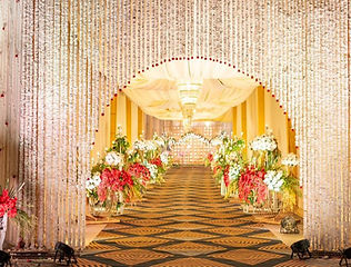 Golden walkway with floral stands and chandeliers by Kauvery Events