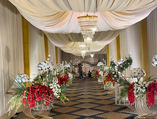 Draped walkway with floral stands at a wedding venue by Kauvery Events