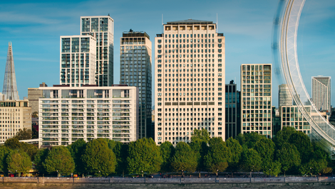 a row of tall buildings with trees in the foreground