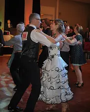 Competitive dance training with a couple practicing ballroom dance in formal competition attire.