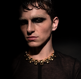 Male model wearing the Jaguar Necklace, an 18k gold-plated bronze necklace with sculptural jaguar heads inspired by Inca, Maya and Aztec aesthetics.