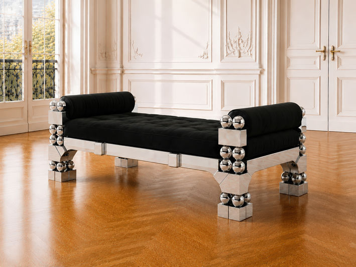 Orbital Daybed, sculptural daybed in polished steel with spherical elements, faceted legs, and black cotton velvet upholstery, full view in a Parisian style empty home with walls with off white boiserie and open windows