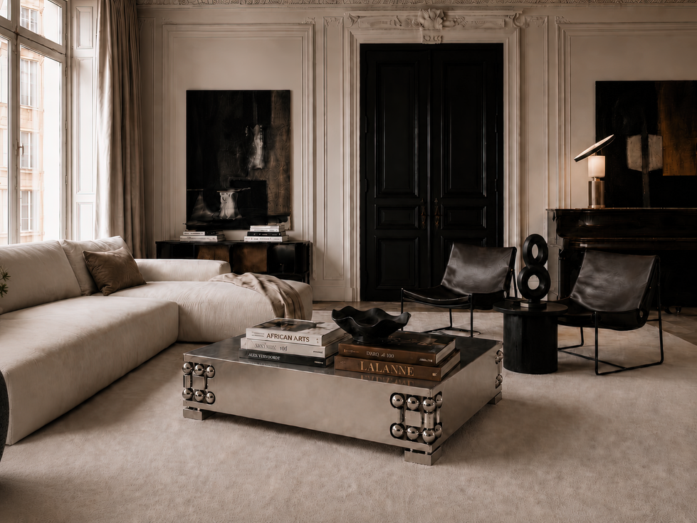 Orbital coffee table no. 2 in polished stainless steel with recessed spherical details, styled in a Parisian living room with cream sofa, dark leather chairs, art books, abstract sculpture, and black double doors.
