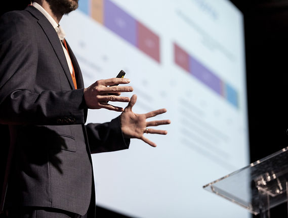 Close up of speaker giving presentation with slides in background