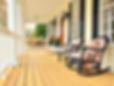 Low angle view of a large front porch with furniture and potted plants. Vertical format..j
