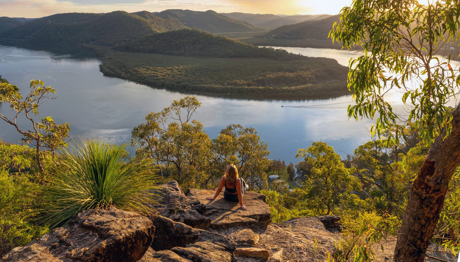 Woman on rocks overlooking scenic Australian river view.