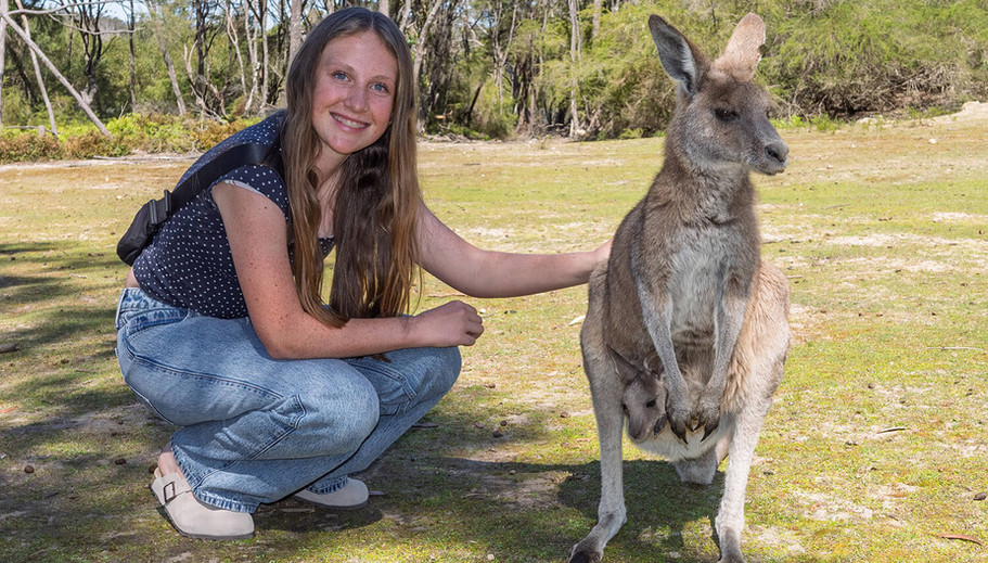 Smiling woman petting kangaroo with joey in pouch