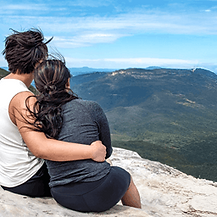 A couple embracing whilst looking into distant valleys and mountains.
