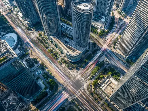 An aerial view of a glowing financial district representing capital flows, illustrating India's relaxation of Press Note 3 FDI rules for Chinese-linked investment