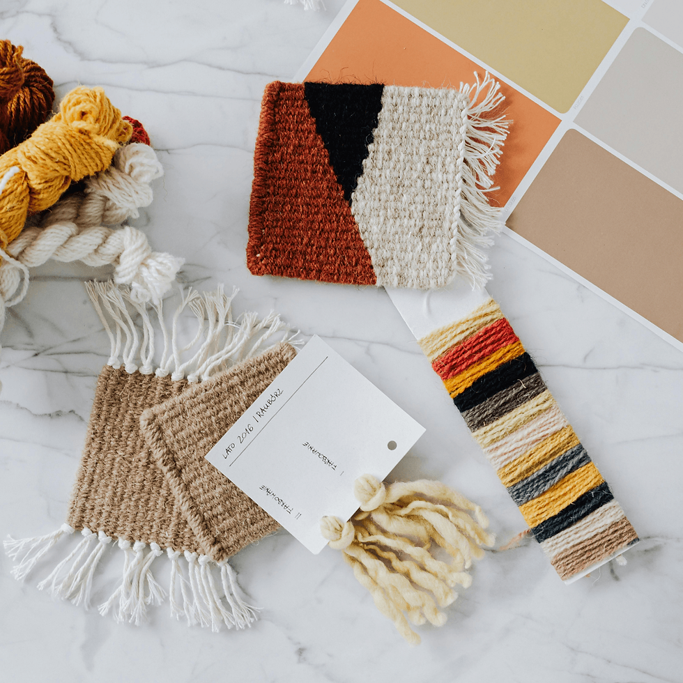Woven fabric swatches in earthy tones on a marble surface. Yarn bundles and color palette card. Labels read "AND 2016 TMAMAK".