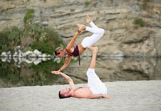 AcroYoga on the Road performing an acro yoga pose on a beach in Sicily, Italy
