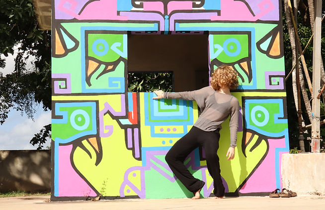 A young woman is dancing in front of a bold painting with bright colors