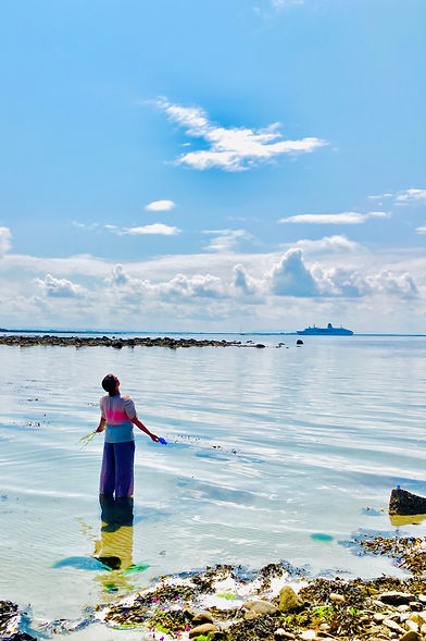 A woman in the ocean is looking up with her arms outstretched